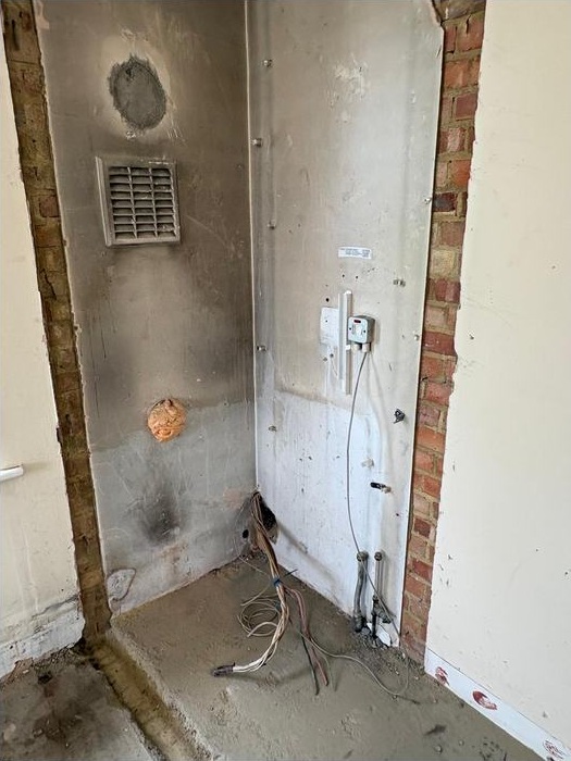 Wall recess and exposed fittings within the New Malden building during strip-out.