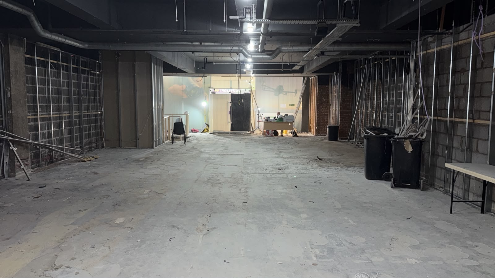 Wide view through the retail unit at 28 Market Street during strip-out, showing exposed wall framing and floor surfaces.